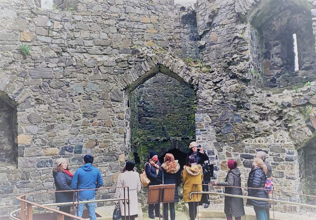 A group of people standing in front of a stone building

Description automatically generated with low confidence