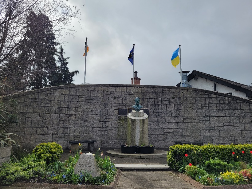 A statue in front of a stone wall with flags

Description automatically generated with medium confidence